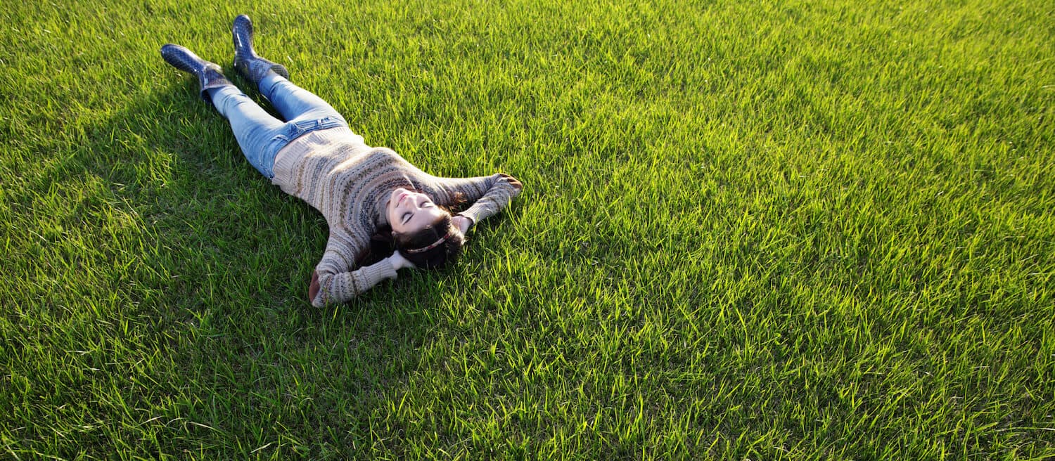 Woman relaxing on healthy green lawn in Edina - stress-free lawn maintenance